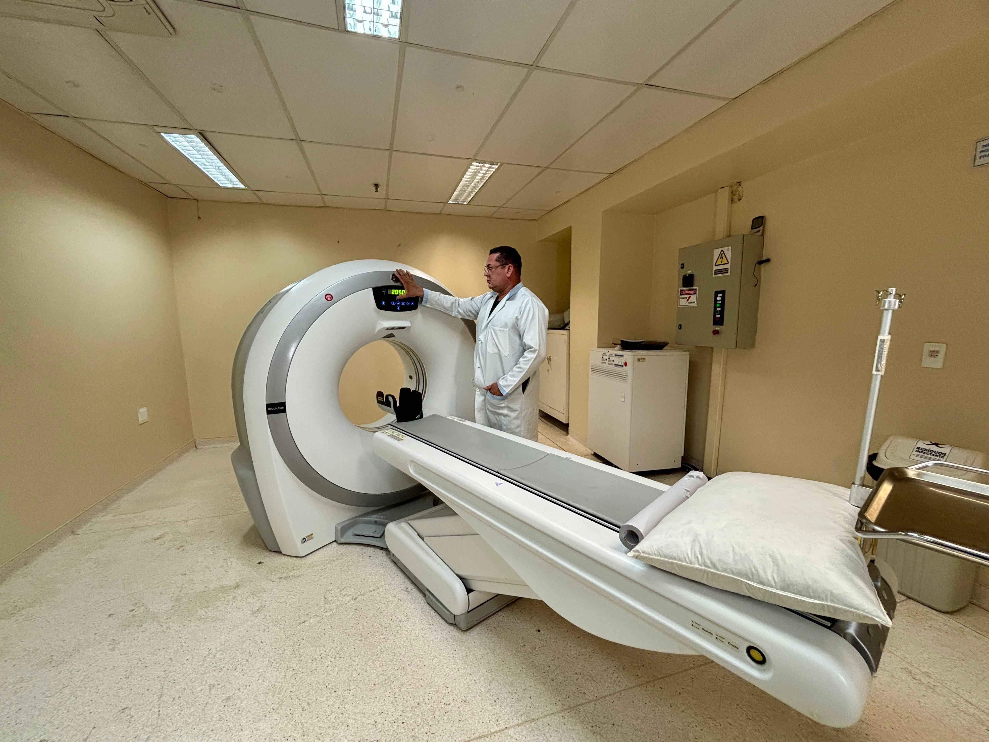 Profissional da Clínica Amor e Vida ao lado do tomógrafo, na sala preparada para o exame de tomografia computadorizada